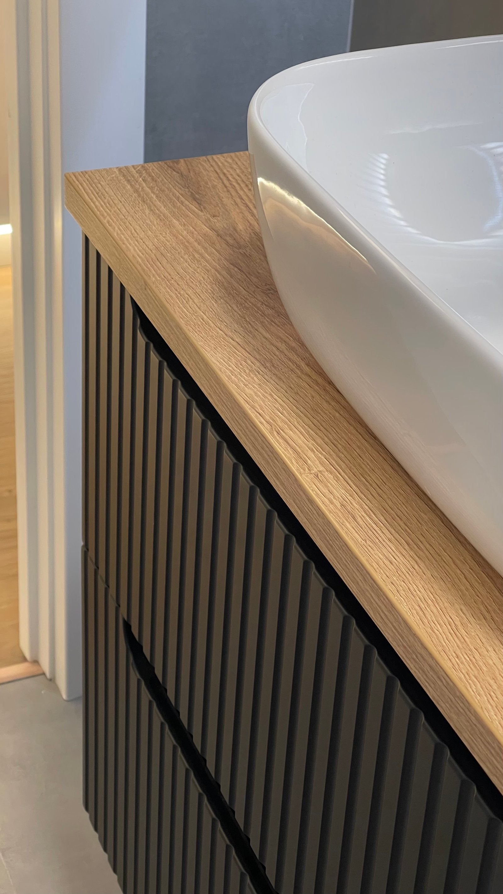 Detalle del mueble de baño estriado en negro con encimera de roble