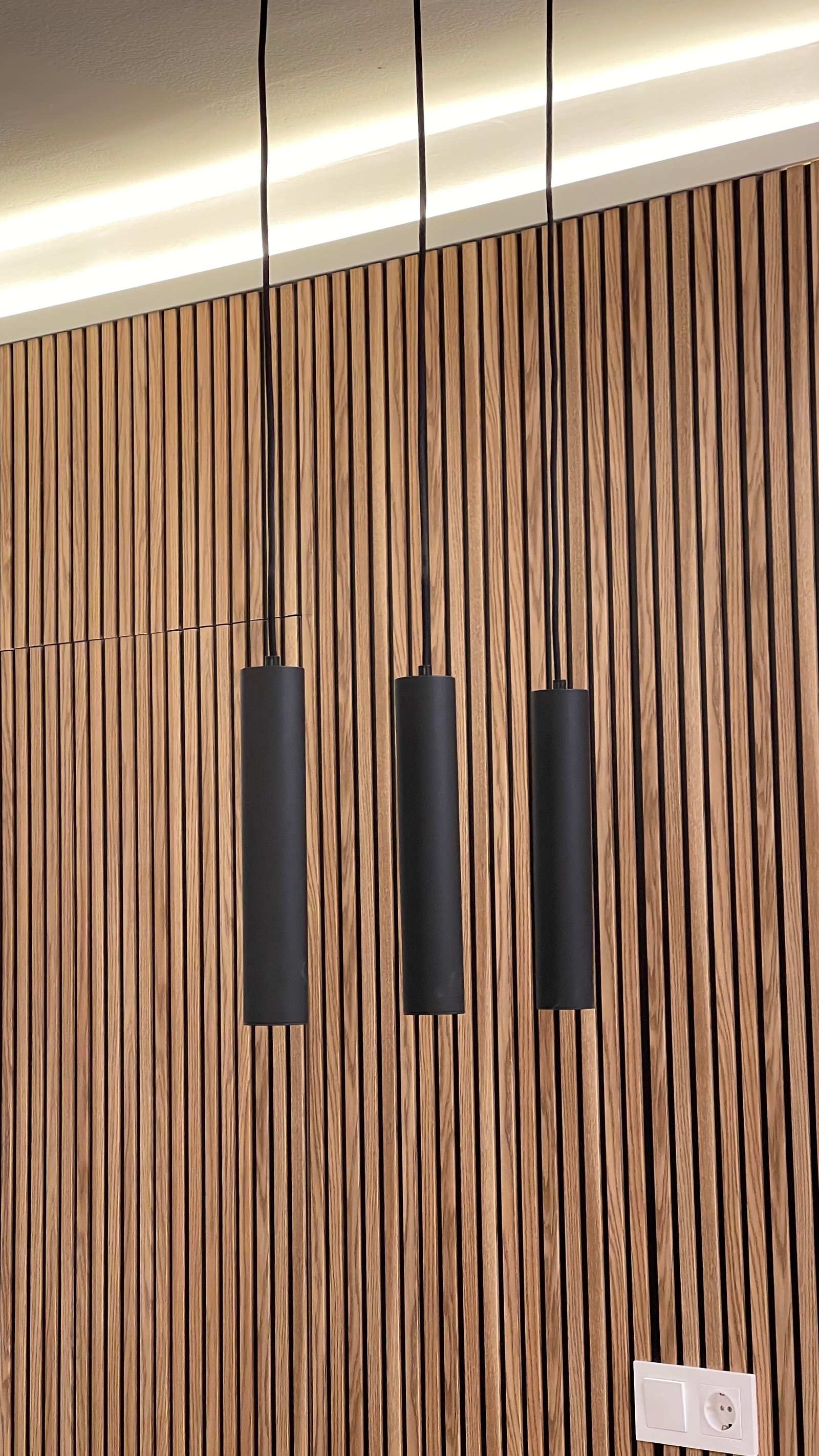 Detalle de las lámparas colgantes negras sobre el panel de listones